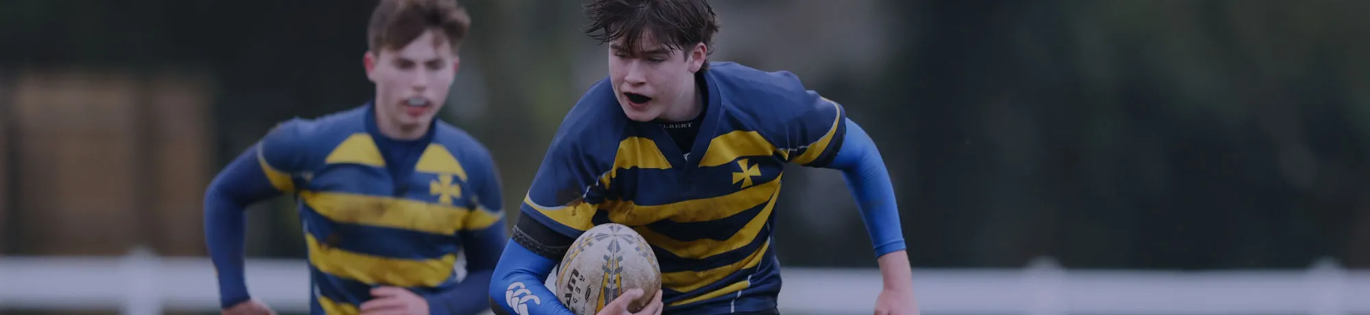 2 boys play rugby in bad weather